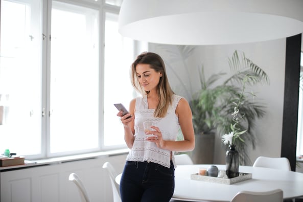 woman-in-white-tank-top-and-blue-denim-jeans-holding-clear